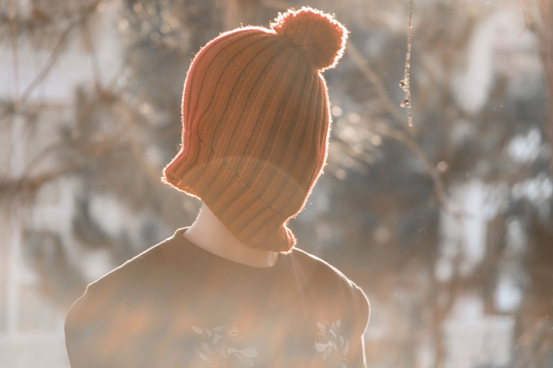Person wearing a warm knit beanie in soft sunlit bokeh