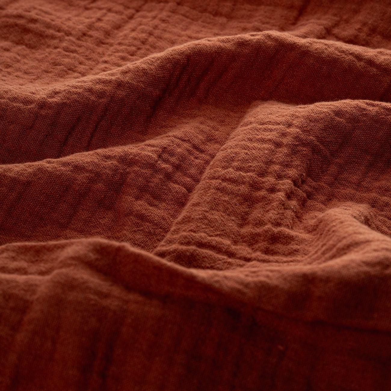 Close-up of warm autumn-colored muslin fabric with soft, textured surface