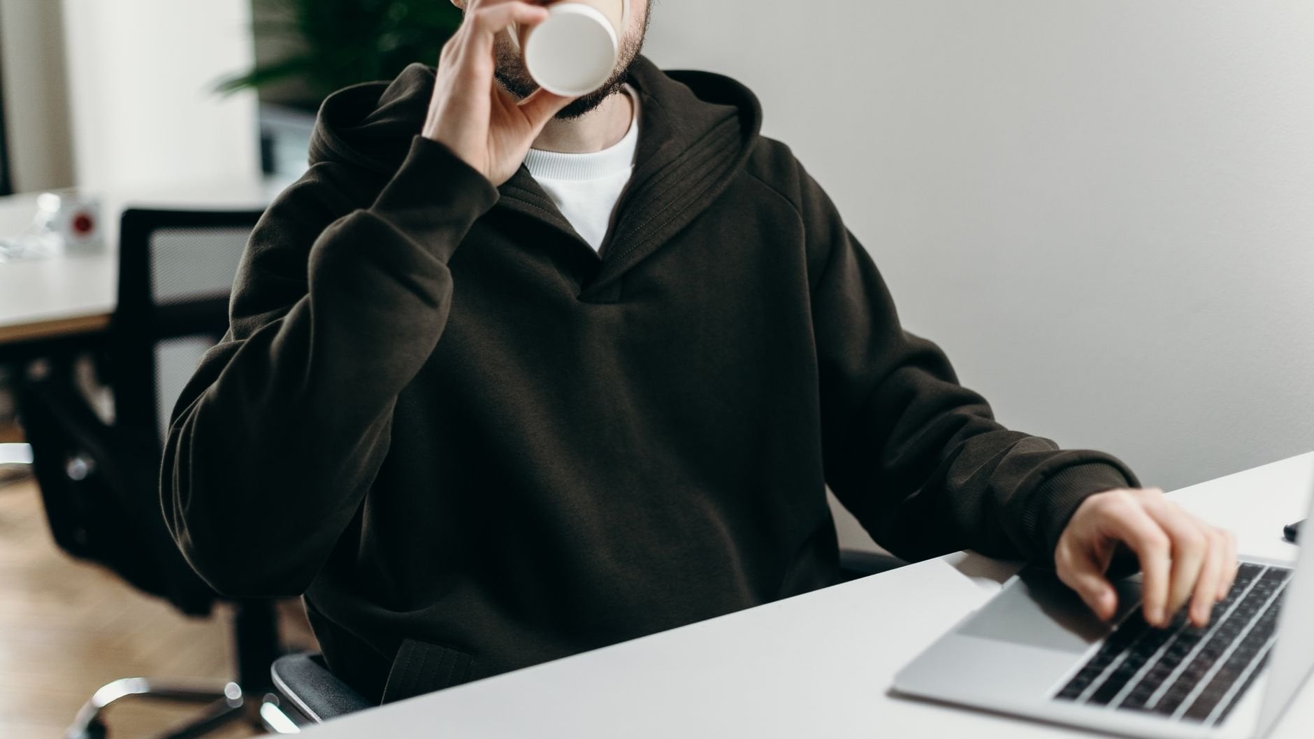 Young freelancer working on laptop with a cup of coffee in a modern home office